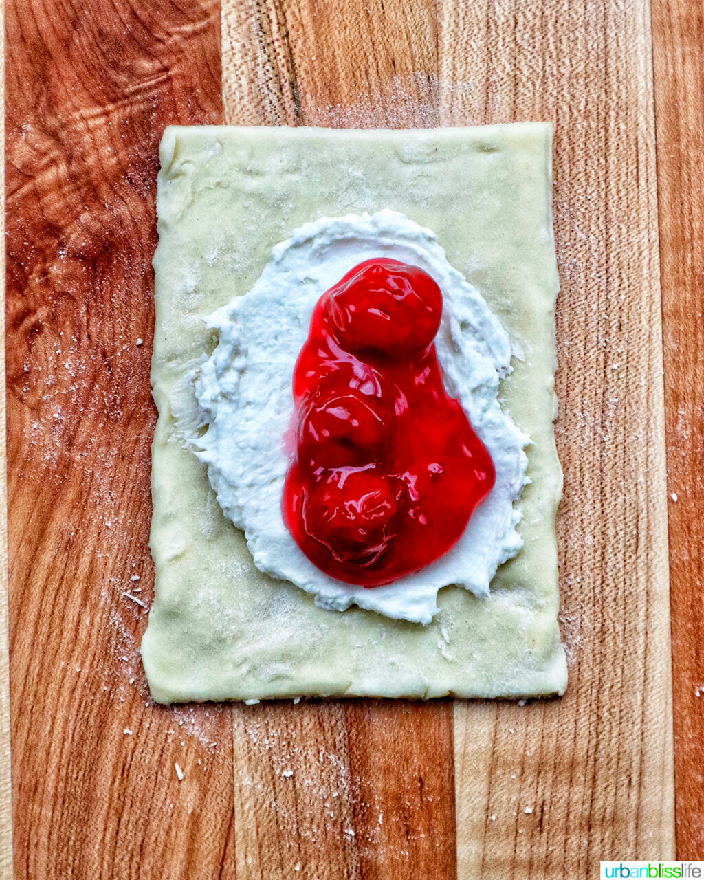 cherry pie filling over cream cheese and puff pastry on a cuting board.