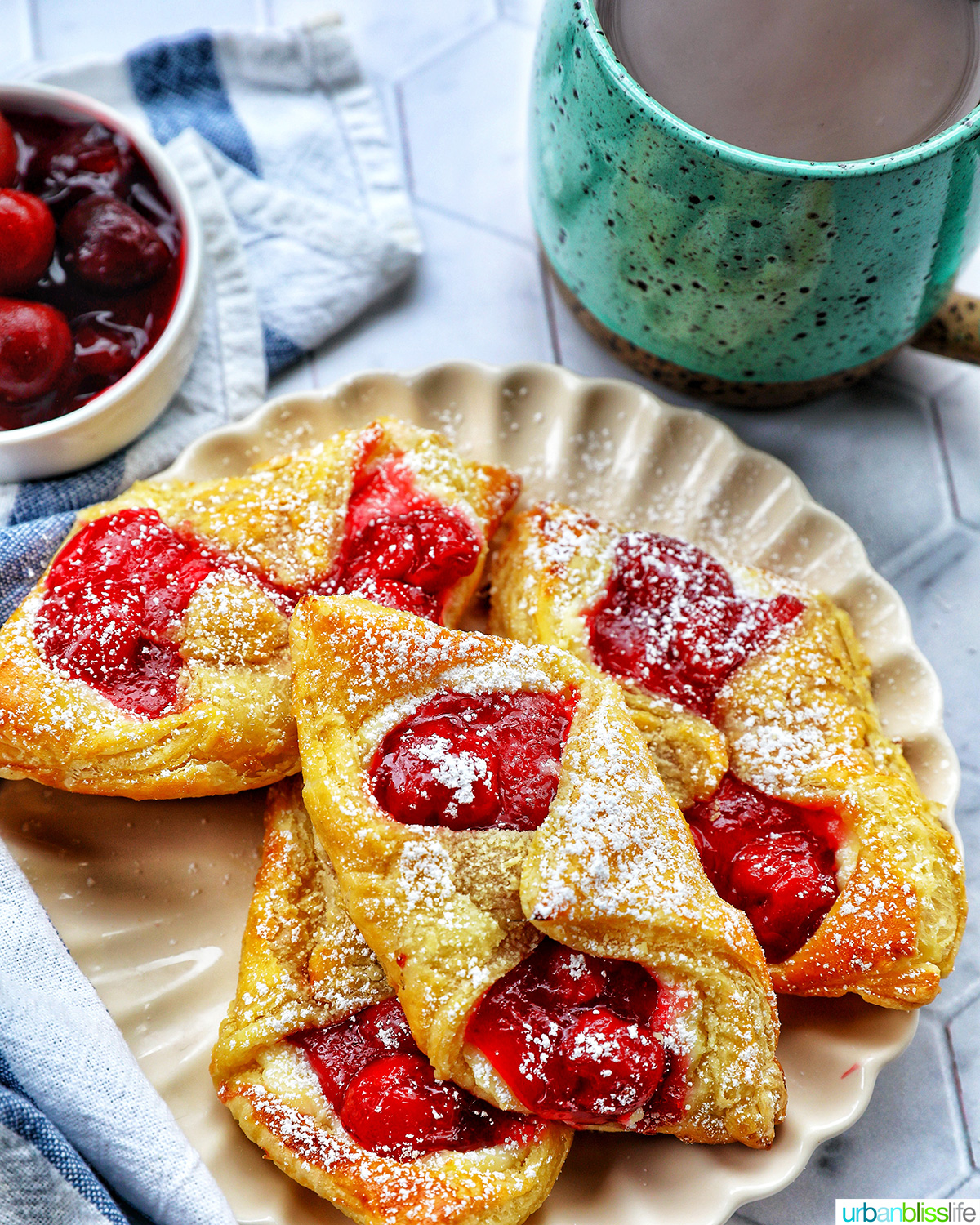 cherry danish pastries on a plate with a cup of coffee.