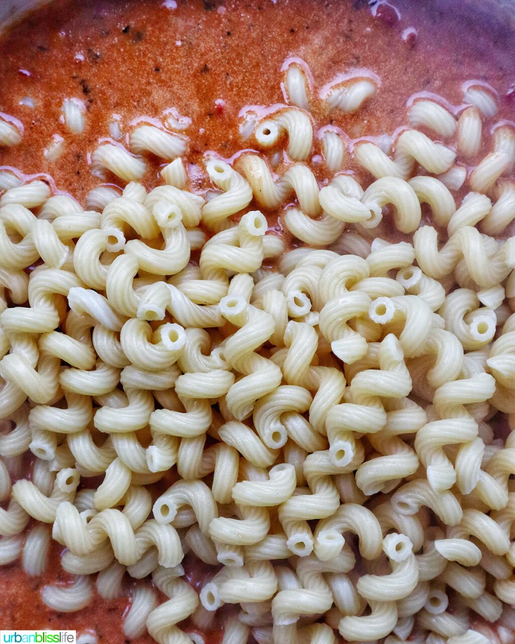 pasta added to chorizo chicken pasta cooking in a pan.