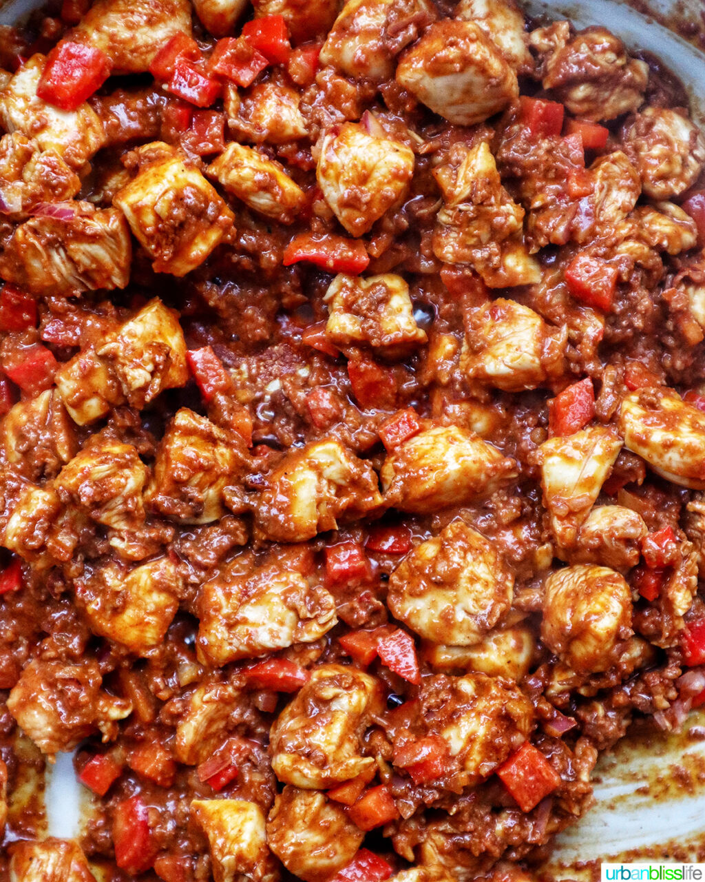 diced red onions and diced red pepper with chorizo and chicken in a pan.