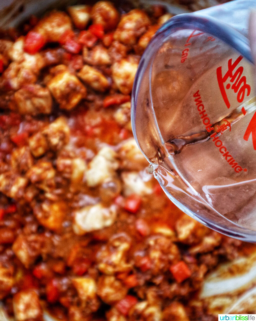 pouring wine into chorizo chicken pasta.