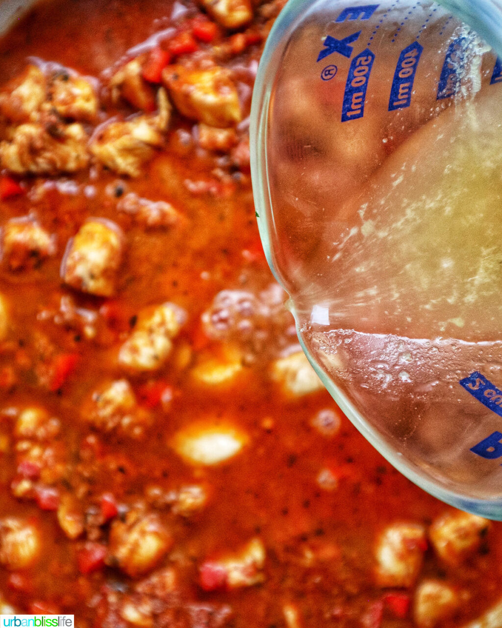 pouring chicken stock into chorizo chicken pasta.