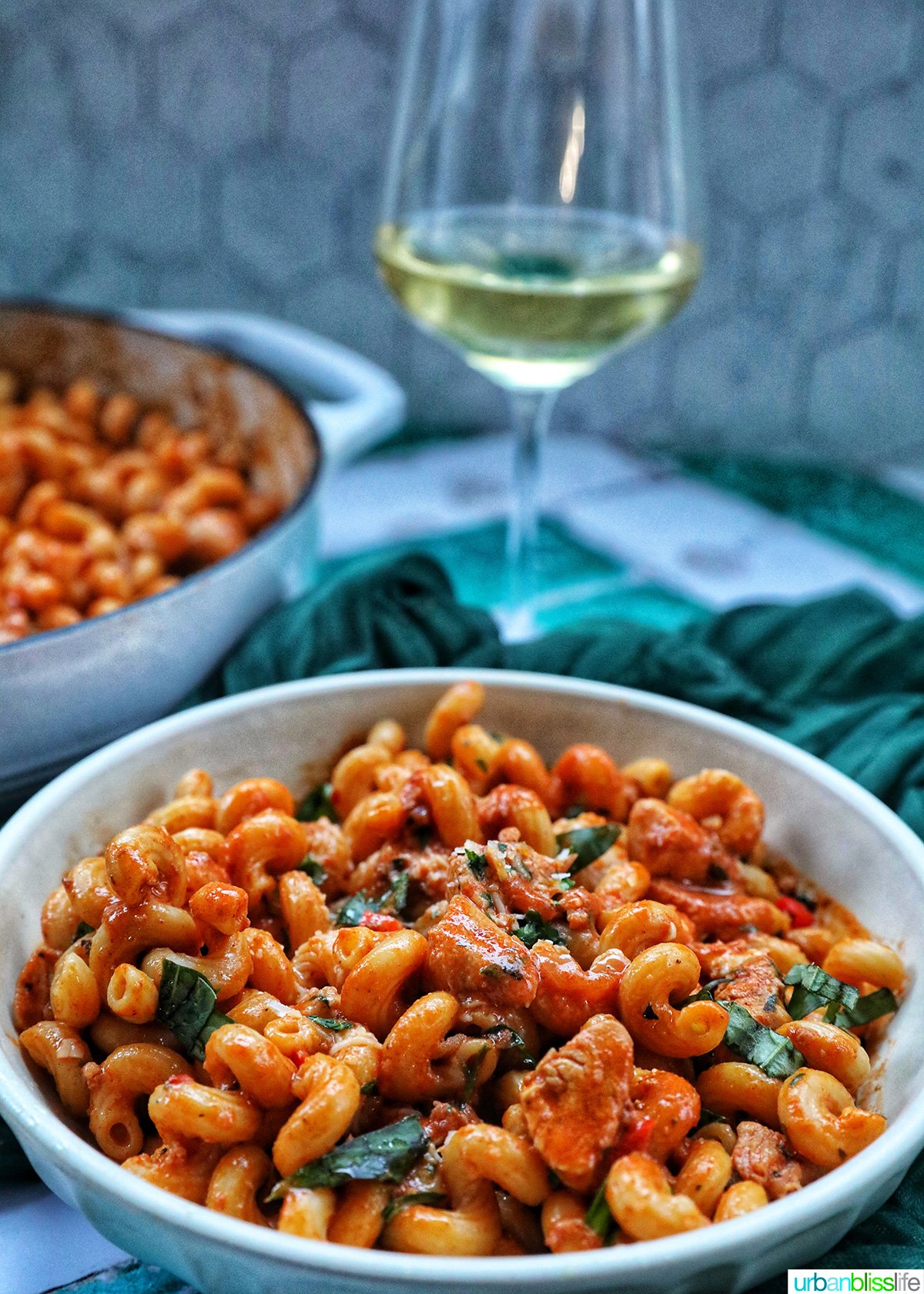 bowl and pan of chorizo chicken pasta with glass of white wine