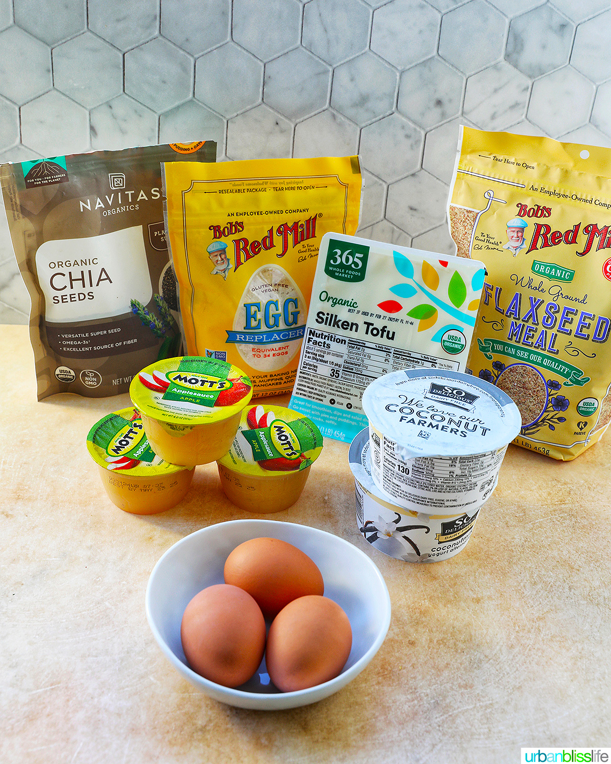 several egg substitutes and egg replacement ingredients plus a bowl of eggs.