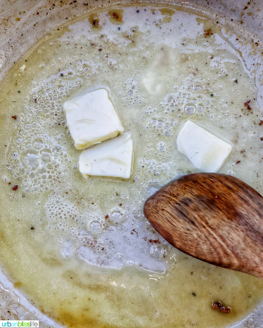 wooden spoon stirring butter in a pan.