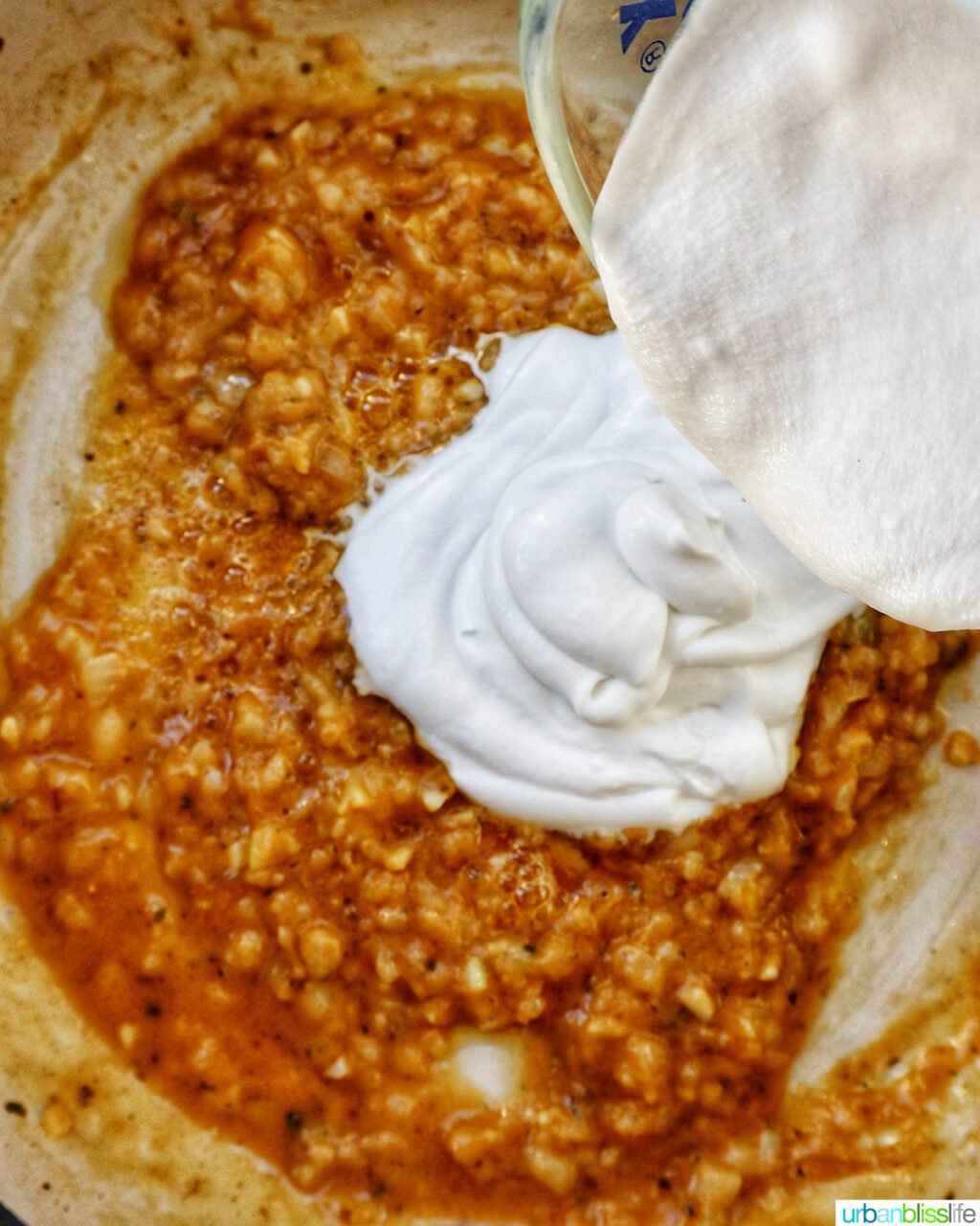 pouring cream over garlic and onions sauteing in butter.