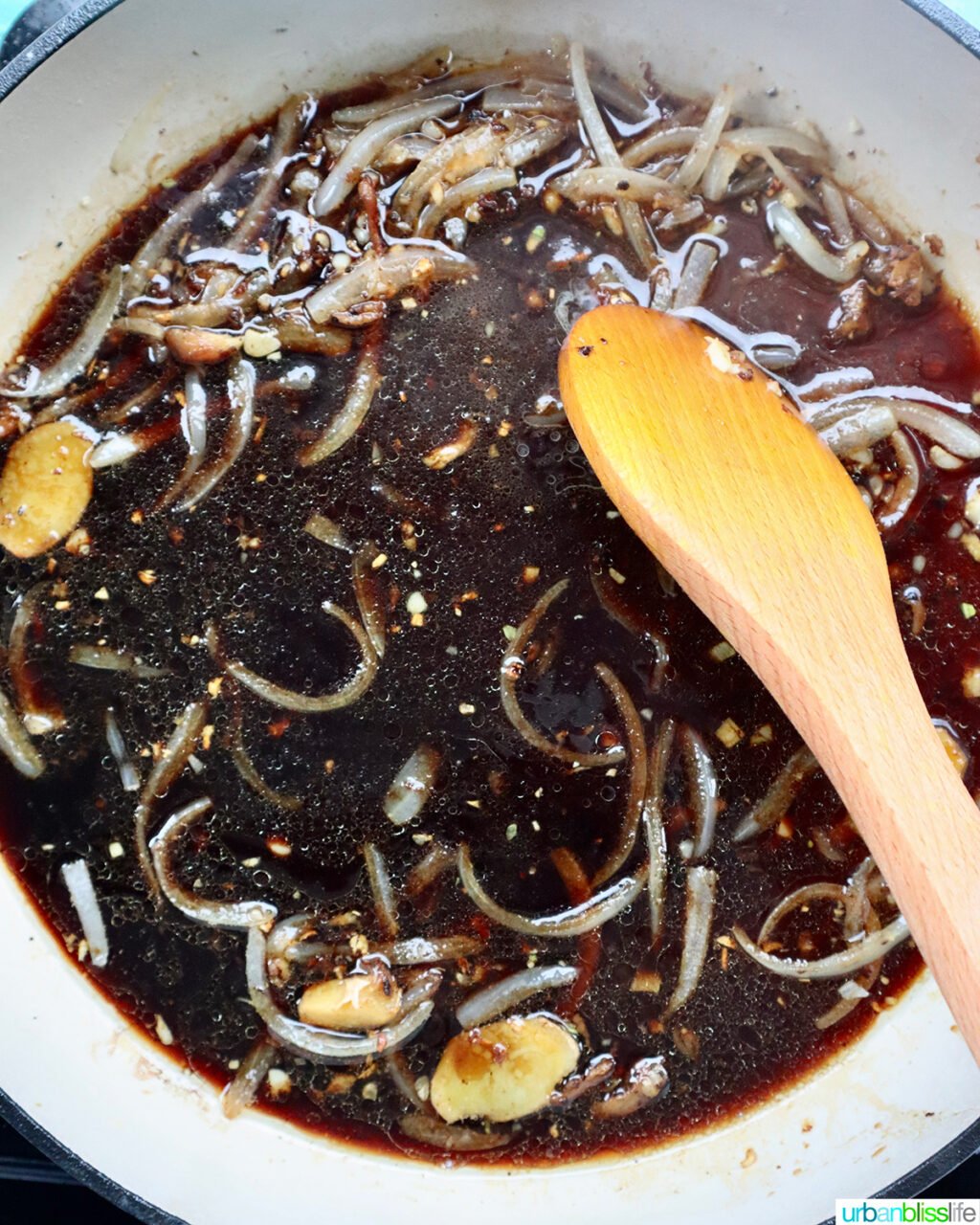 wooden spoon stirring sauce in a skillet.