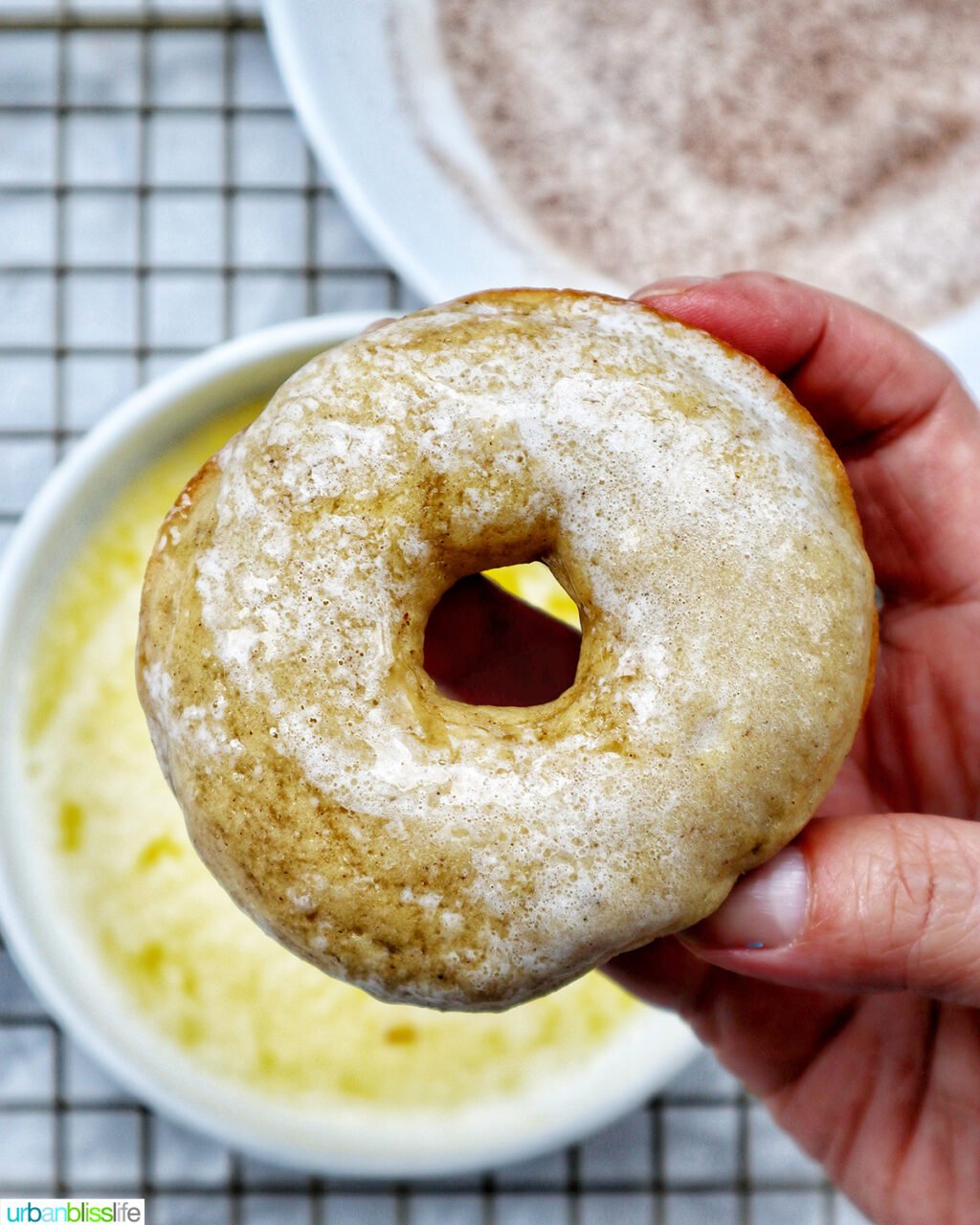 hand holding a churro donut dipped in melted butter.