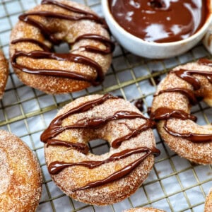 churro donuts on a cooling rack with chocolate drizzle.