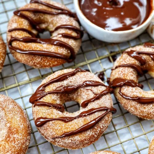 churro donuts on a cooling rack with chocolate drizzle.