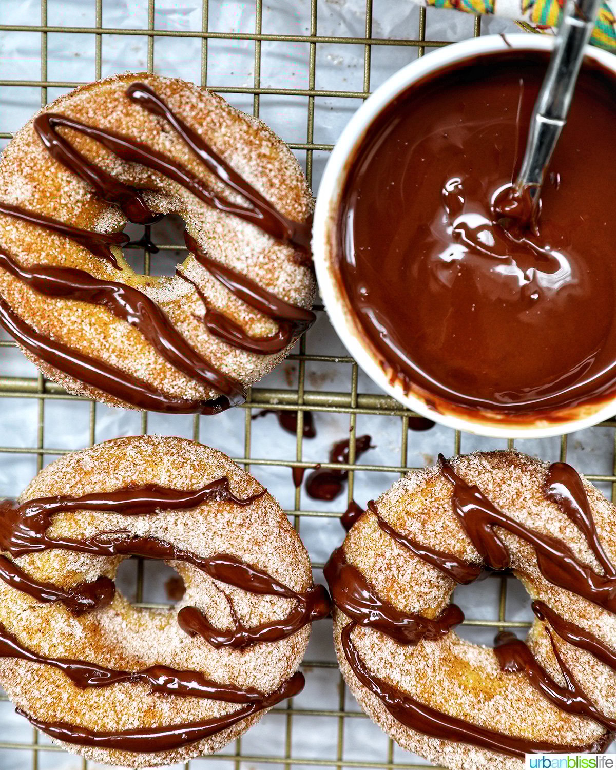 churro donuts on a cooling rack with chocolate drizzle.