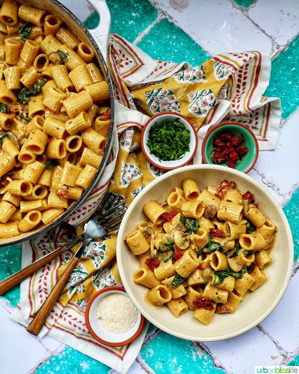 bowl of vegetarian Marry Me Pasta with bowls of garnishes forks, and a pan of pasta.