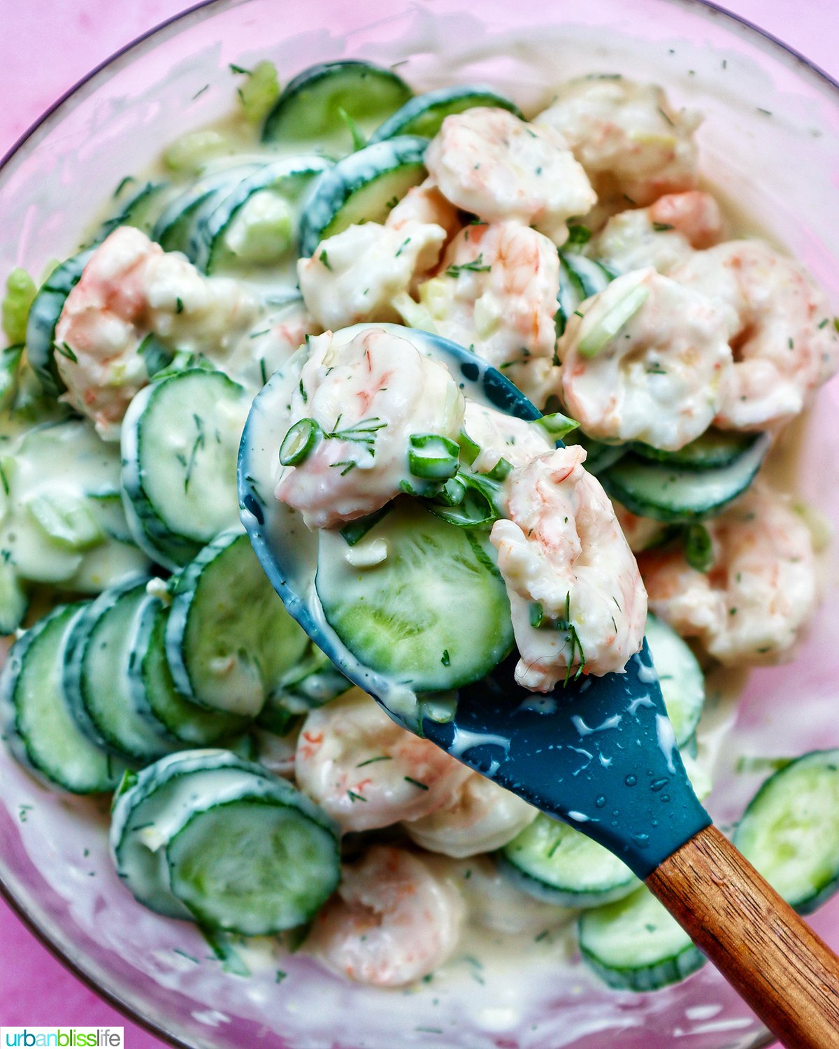 spoon of cucumber shrimp salad above a bowl.