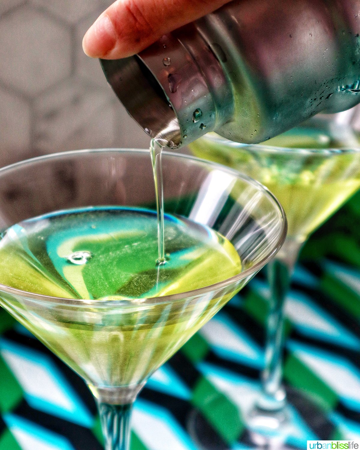 pouring dill pickle martini into a martini glass.