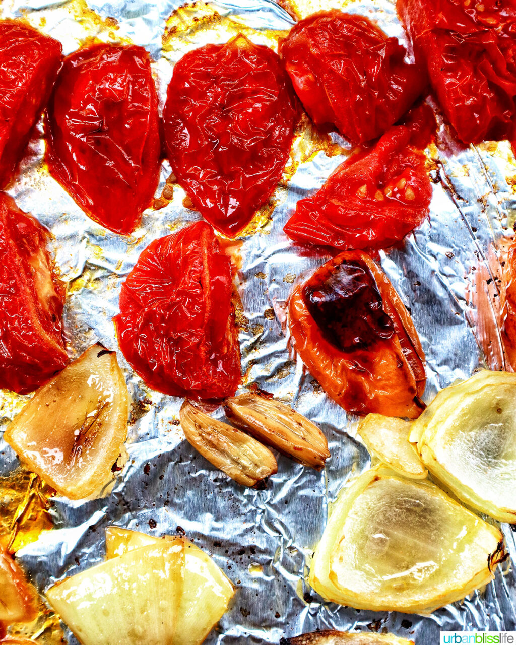 roasted sliced tomatoes, onions, habanero, and garlic on a baking sheet.