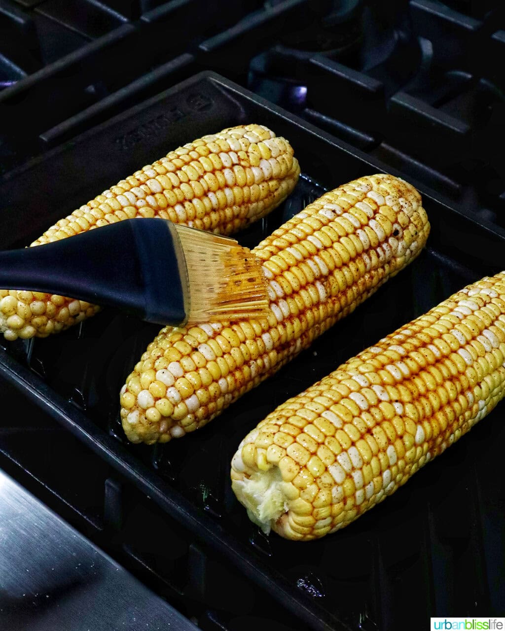basting corn on the cob on a grill pan.