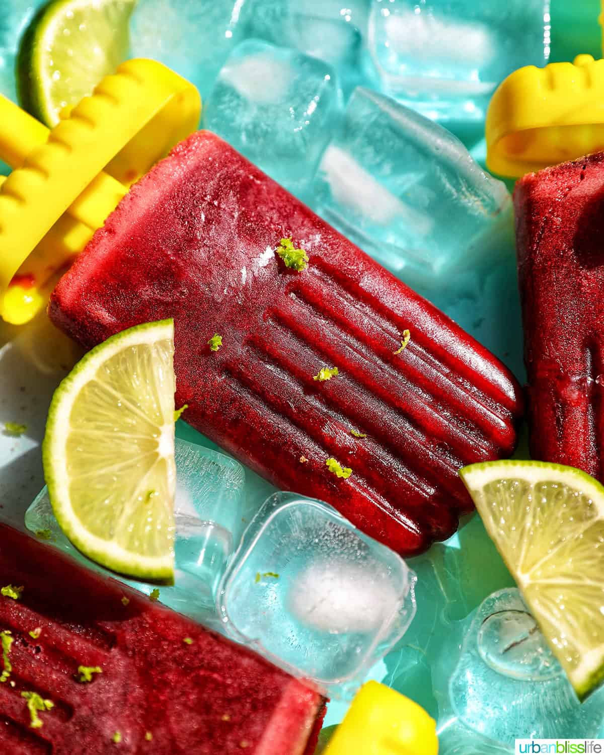 cherry popsicles on ice with slices of lime.