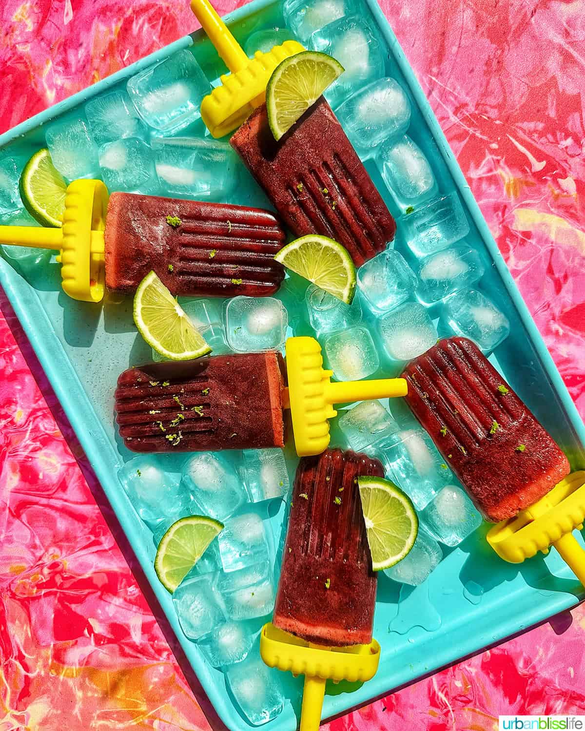 cherry popsicles on ice with slices of lime.