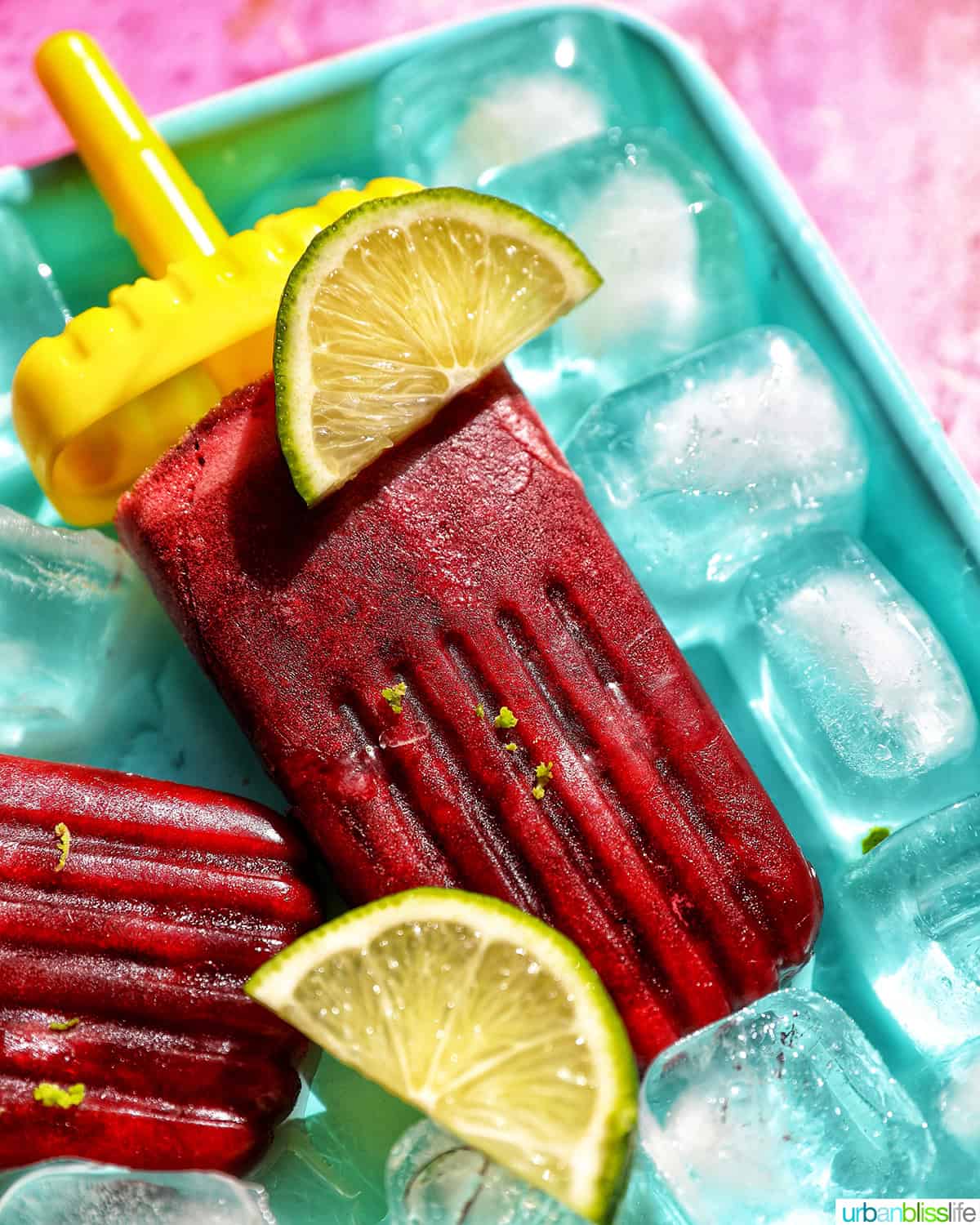 cherry popsicles on ice with slices of lime.