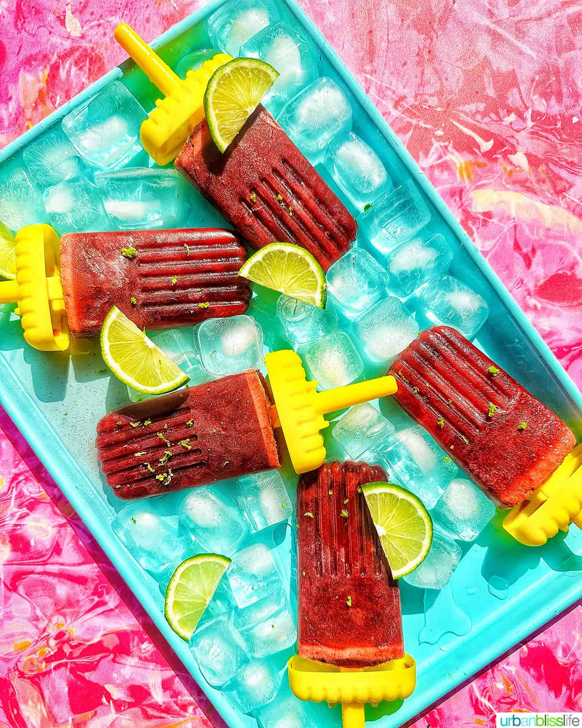 cherry popsicles on ice with slices of lime.