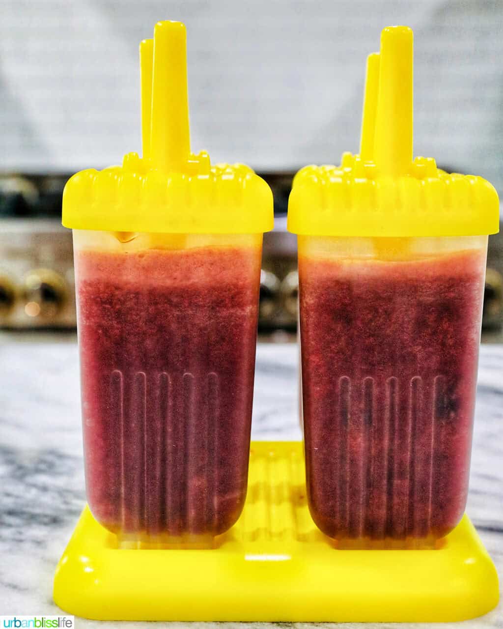 cherry popsicles in popsicle molds on a kitchen counter.