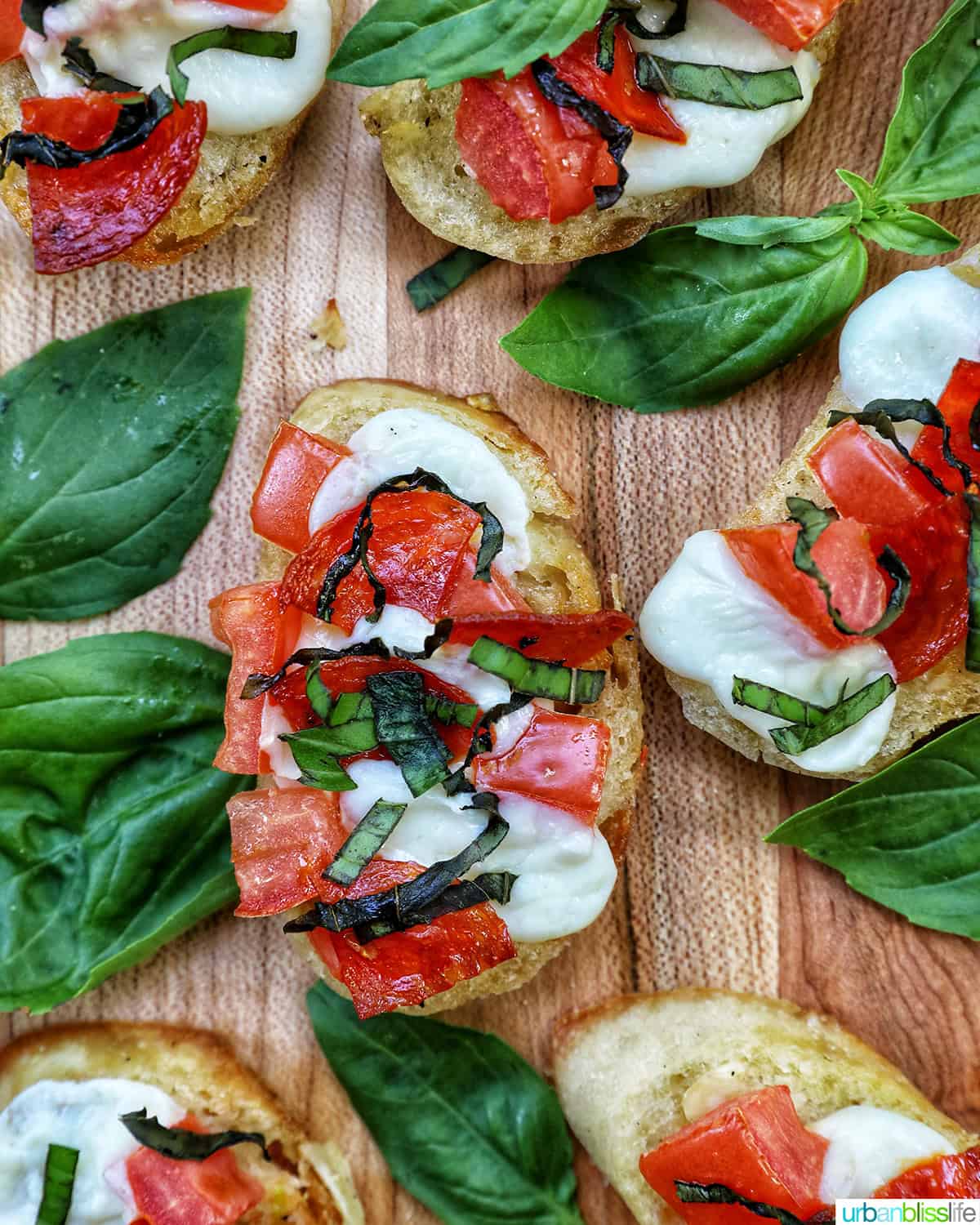 lots of crostini pizzas on a wooden board with a side bowl of salt.
