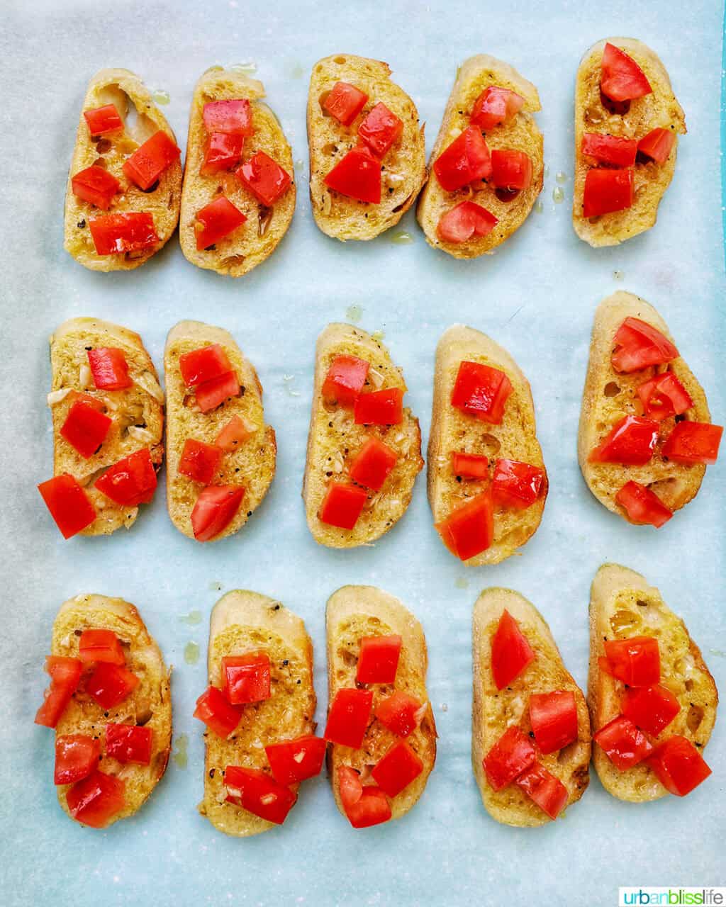 sliced crostini on a baking sheet topped with tomatoes.