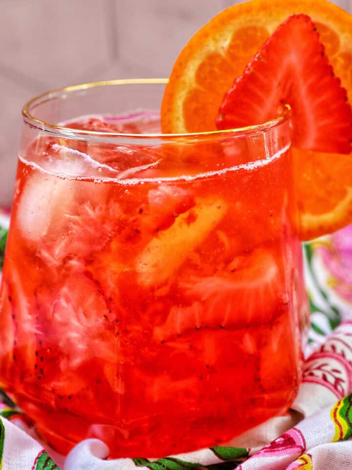 strawberry spritz with orange and strawberry garnish.