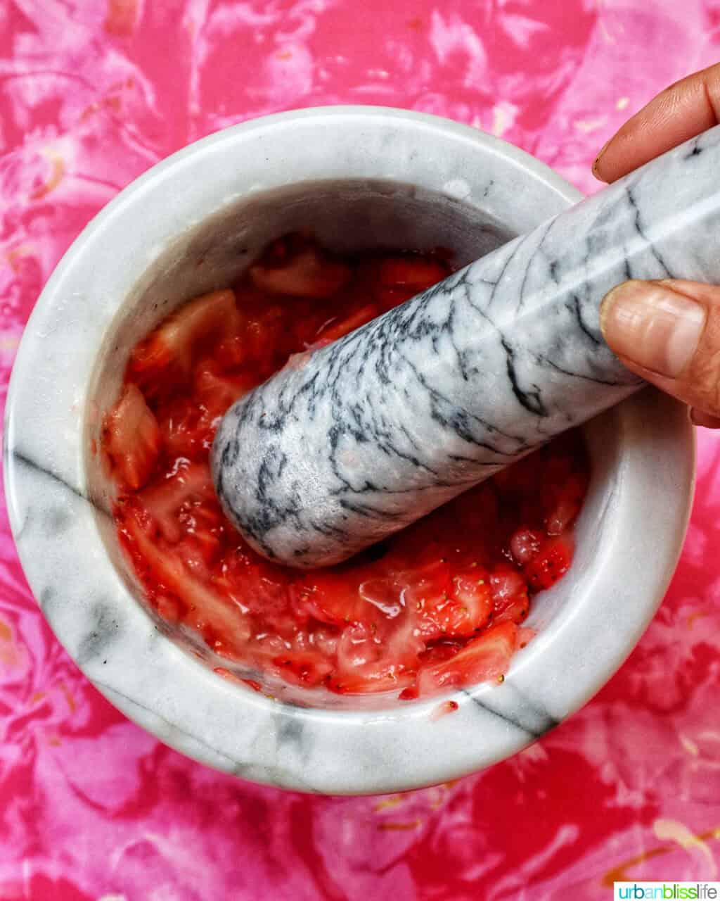muddling strawberries in a mortar and pestle.