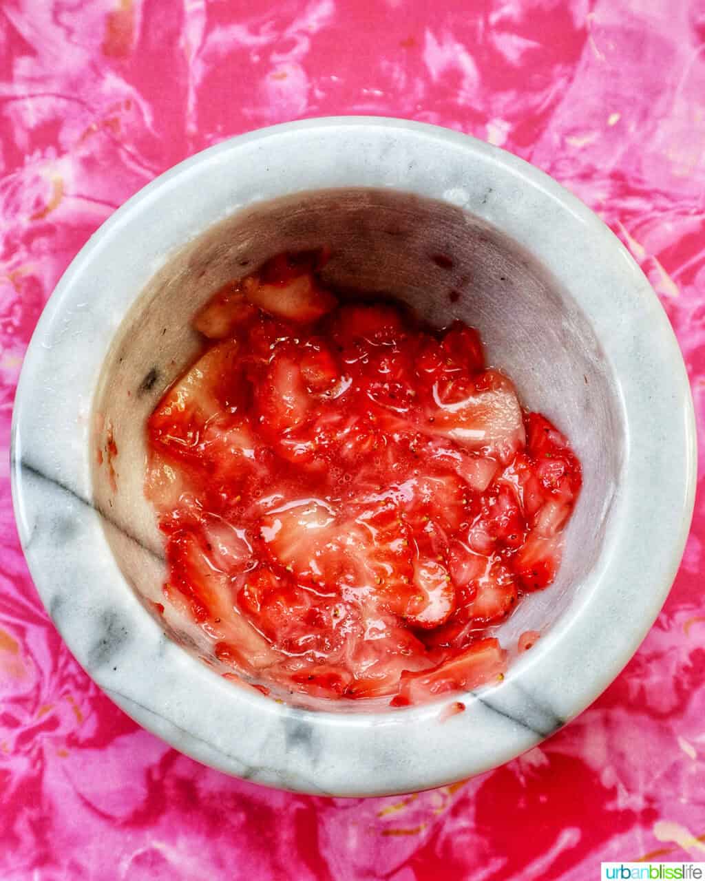 muddling strawberries in a mortar and pestle.