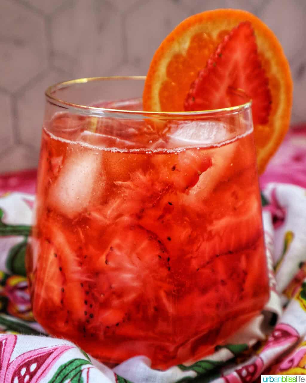 strawberry spritz with orange and strawberry garnish.