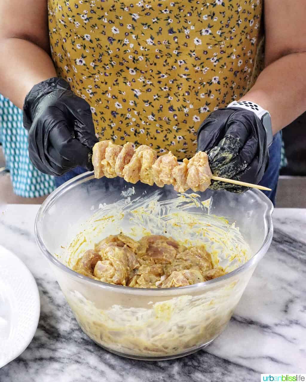 threading marinated chicken onto a skewer.