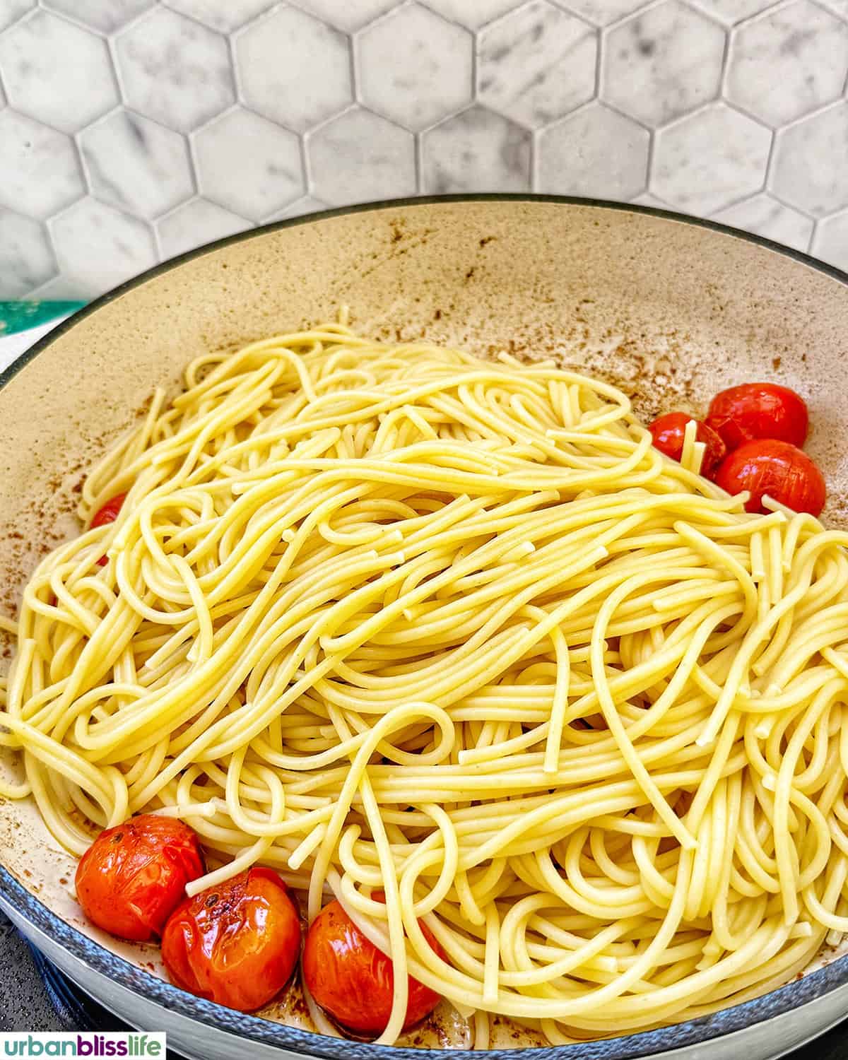 spaghetti pasta with cherry tomatoes in a pan.