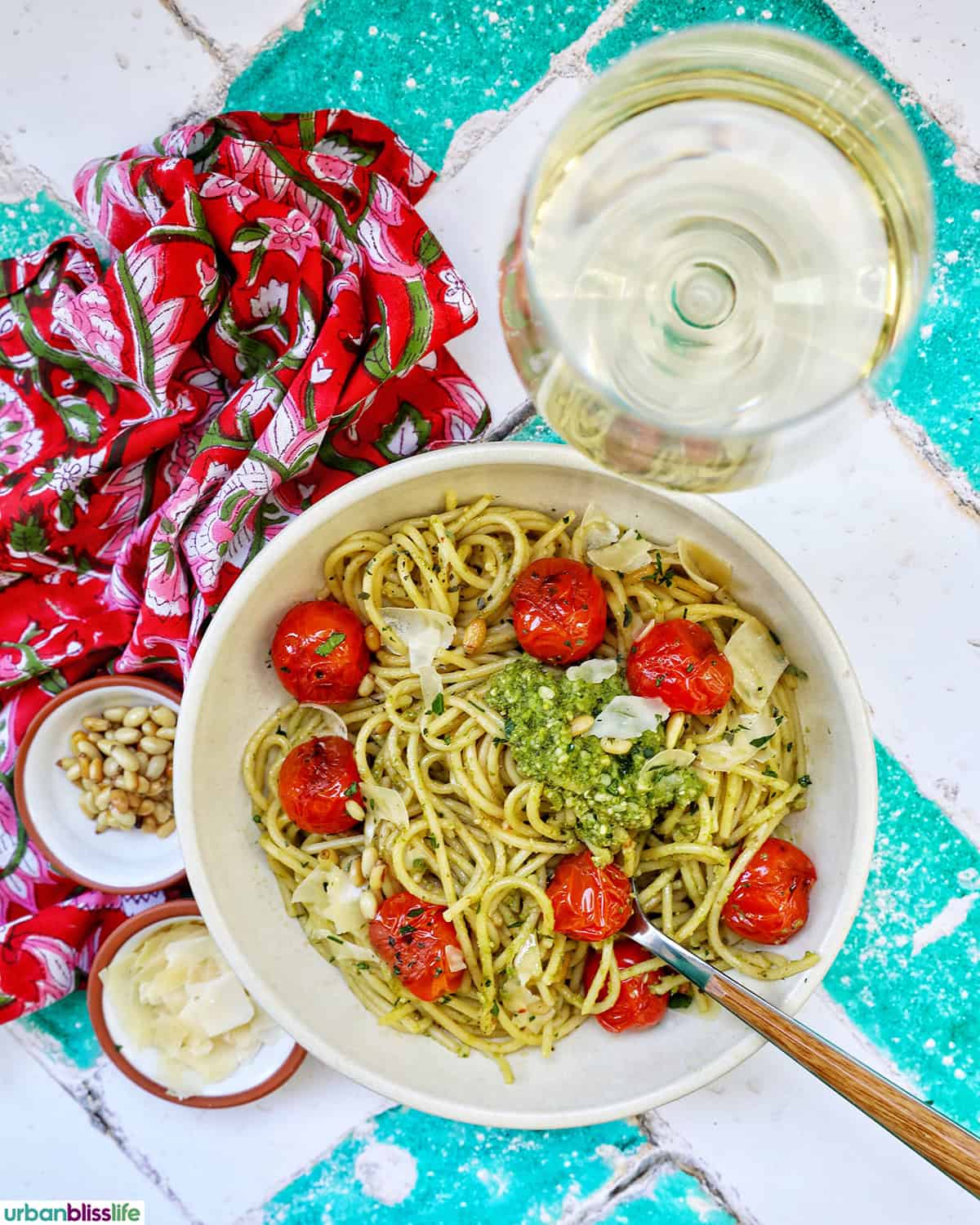 bowl of cherry tomato and pesto pasta with a glass of white wine.