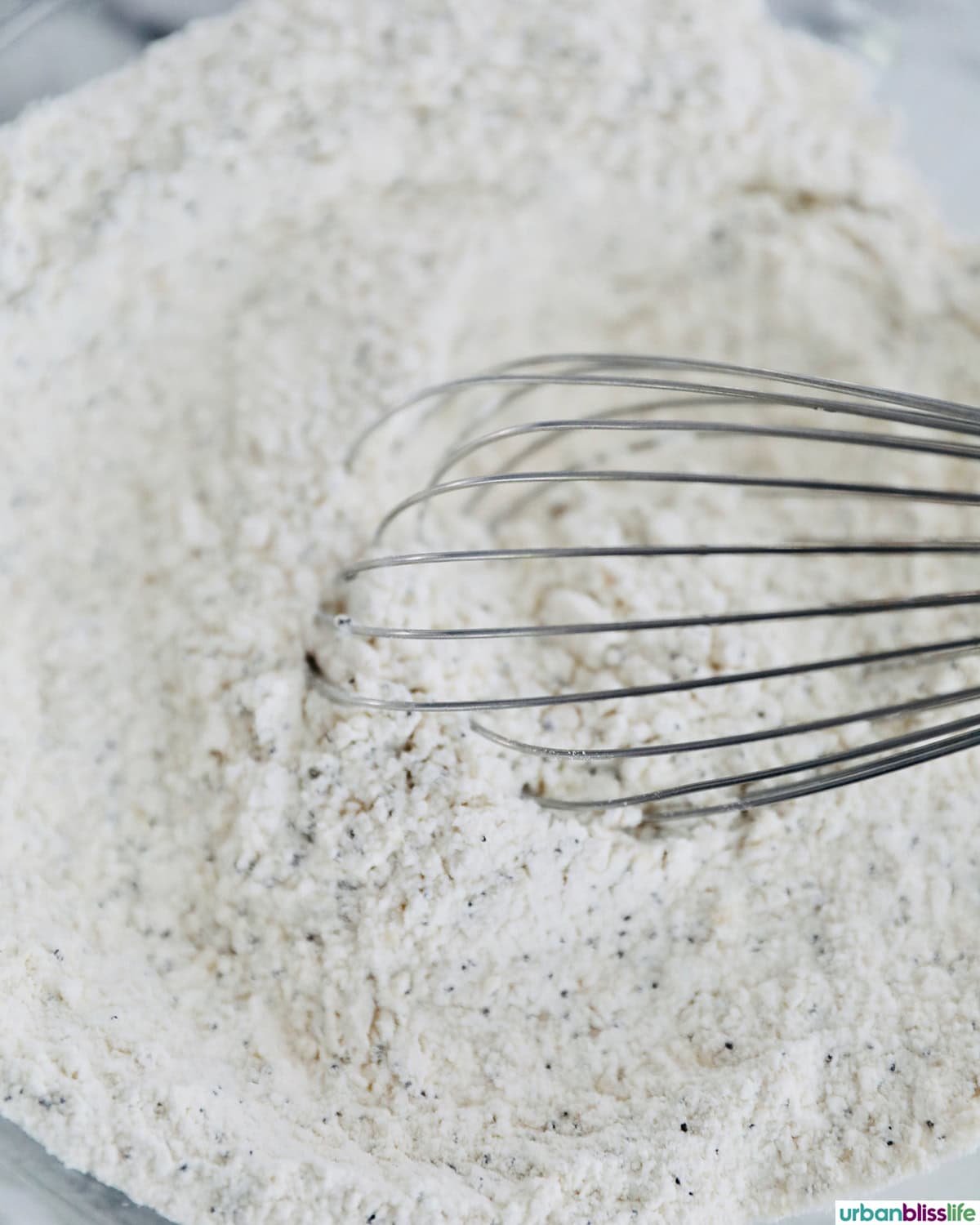 whisk in a bowl with sesame crackers dough.